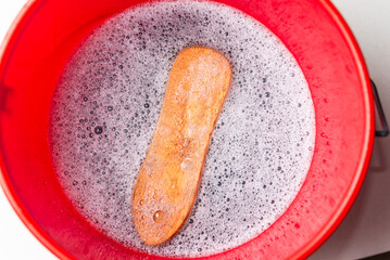 scrubbing brush in cleaning bucket filled with water and soup with foam 
