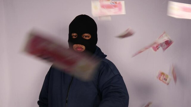 close up on the thief throwing away his bundles of 100 renminbi or chinese yuan banknotes and wearing a jacket with a white background.

