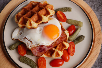 Breakfast waffles with fried eggs Tomatoes and pickled cucumbers In a white plate with a black background