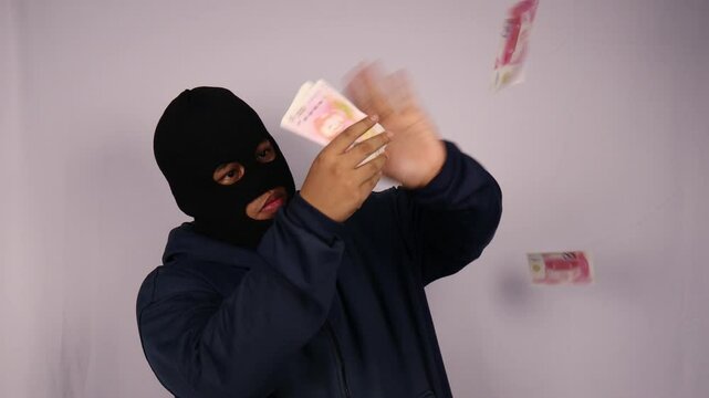 close up on the thief fanning out his bundles of 100 renminbi or chinese yuan banknotes and wearing a jacket with a white background.
