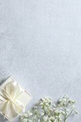 Top view photo with gypsophila flowers and gift box on gray background 