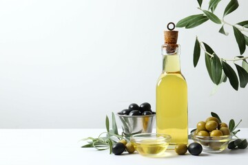 Bottle of fresh olive oil and olives with leaves on the table