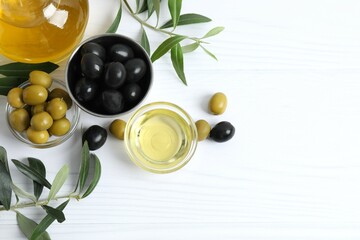 Bowl of fresh olive oil and olives with leaves on the table
