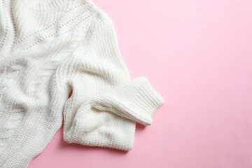 White knitted sweater on paper color background top view copy space. Texture of woolen cotton winter autumn cozy sweater, clothes. Knitted jumper, pullover, fashion. Sweater close-up