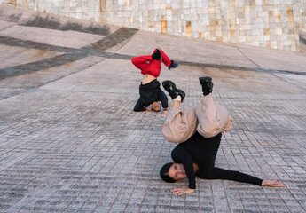 A woman striking a breakdance pose on the floor. A man strikes another pose behind her