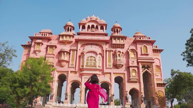 Indian woman wearing Saree walking towards Patrika Gate in Jaipur, Rajasthan, India. Tourist exploring Pink City Jaipur. Beautiful old architecture. Travel and holidays concept.