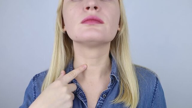 Thyroid disease. Woman points to her neck where the thyroid gland is located. Examination and monitoring of thyroid hormones