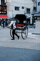 Obraz premium Traditional Rickshaw in an Urban Setting, Capturing the Essence of Cultural Heritage and Daily Life in a Bustling City Environment with Pedestrian Activity