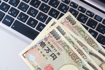 パソコンのキーボードと一万円札で、インターネットを活用してネット上で自由にビジネスを展開するイメージ
