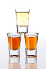 Stack of three shot glasses with different liquors, isolated