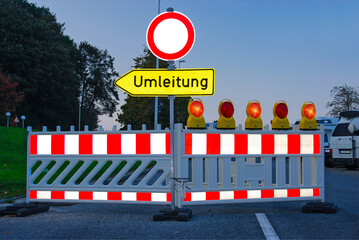 Roadworks illuminated by headlights at dusk with detour signs and flashing lights. - 2338