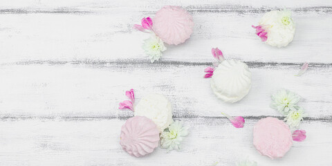 Fruit marshmallow with fresh flower petals on white wooden background. Lactose free vegan dessert