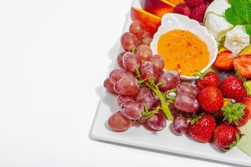 Assorted cheese plate with fruits and sauces isolated on white background. Vegan snacks concept