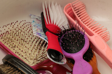 A collection of various hairbrushes and combs, showing signs of use and wear.  Different styles and colors are present.