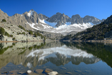 Stunning reflection of snow-capped mountains in tranquil lake during bright sunny day. Generative AI