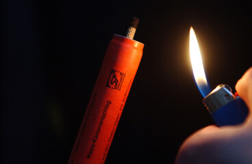 Entz&uuml;nden eines Feuerwerksk&ouml;rpers mit einem Feuerzeug. / Lighting a firework with a lighter.