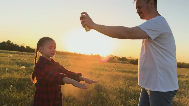 Father protect child with spray against mosquitoes, midges. Man dad spray on child kid daughter protect skin body from bites of mosquitoes, midges. Necessary measures for comfortable pastime in nature