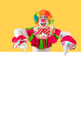 Funny clown pointing sign blank template mock up for advertising, posters, greetings, invitations. Entertainer as Joker in a suit and wig, with clown whiteface makeup
