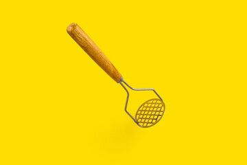 potato masher kitchen equipment tool on yellow background.