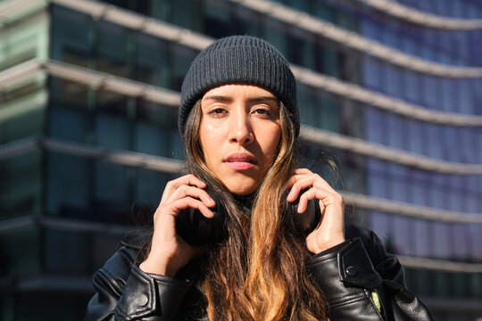 Young woman wearing headphones and beanie in urban setting