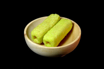 Long green sweet biscuit snack placed in wooden bowl and black background