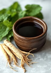 Obraz premium Close-up of a dark brown bowl filled with herbal tea, accompanied by fresh mint leaves and ginseng roots. The image evokes a sense of natural health and wellness.