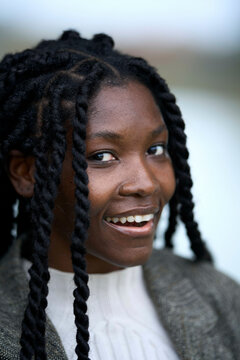 Smiling woman with braided hair wearing a white blouse and grey jacket outdoors, Brandenburg, Germany