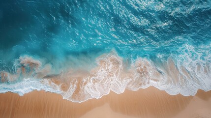 Fototapeta premium Drone shot of a beautiful summer seascape. The blue sea sparkles under the sun, waves gently rolling onto a sandy beach. A perfect scene of tranquility