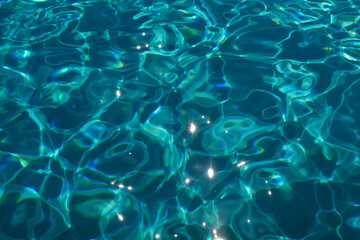 Sunlight reflects on the tran0uil blue water of a swimming pool creating a pattern of light and shadows, Portugal