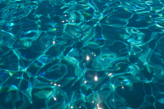 Sunlight reflects on the tran0uil blue water of a swimming pool creating a pattern of light and shadows, Portugal