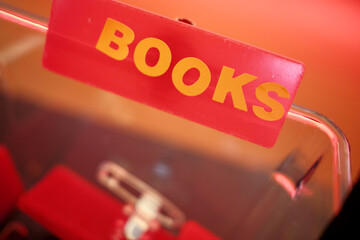 Close-up of a red BOOK' sign against a blurred background with a warm hue.