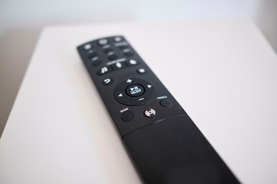 Black remote control resting on a white surface with buttons in focus.