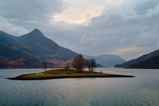 Loch Leven, a serene lake with a small island under a cloudy sky, surrounded by mountains at dusk, Scotland