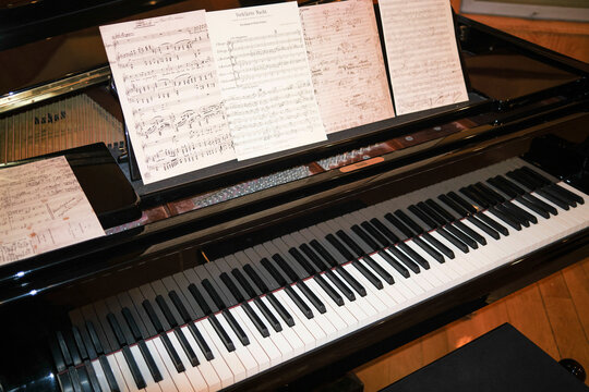 A grand piano with sheet music on the stand ready for a musician to play.