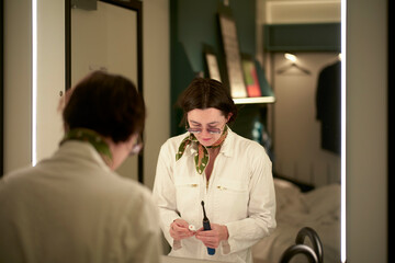 Woman preparing to brushing teeth in front of a bathroom mirror with reflections and soft lighting