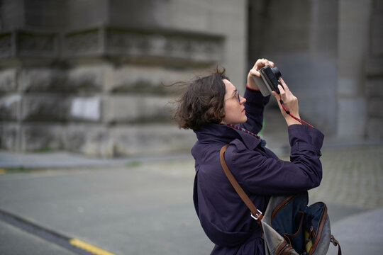 Photographer in a purple jacket capturing images with a camera on an urban street, Berlin,. Germany - Powered by Adobe