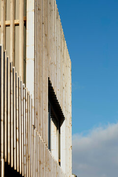 Sunset light casting shadows on the modern architecture of a building with vertical lines and blue sky in the background, Berlin, Germany