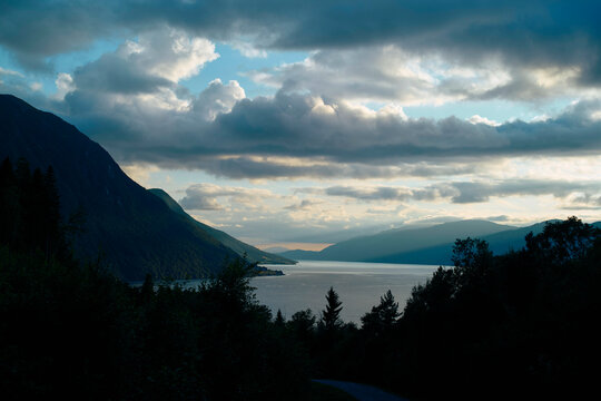 Sunset over a tran0uil fjord with clouds partially obscuring the sun, Romsdalfjorden, Norway