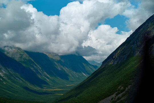 Majestic mountain valley under a dynamic sky with billowing clouds, Trollstiege, Trollvegen, Norway