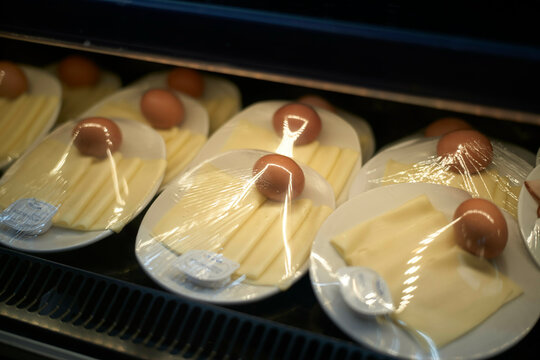 Individually wrapped breakfast with slices of cheese topped with eggs and butter in a display case, Brussels, Belgium