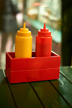Red and yellow condiment dispensers in a holder on a wooden table with a blurred background, Vienna, Austria