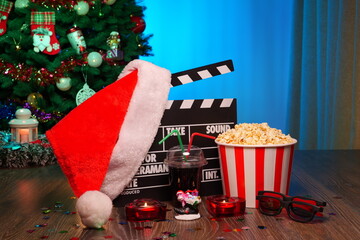 Merry Christmas and New Year Holidays Scene. Santa Claus Hat, Movie Clapperboard, Christmas Tree, Garland, Neon Lights, Cinema Popcorn, and 3D Glasses. Perfect Setting for Holiday Movie Nights at Home
