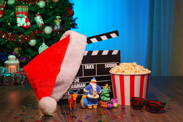 Merry Christmas and New Year Holidays Scene. Santa Claus Hat, Movie Clapperboard, Christmas Tree, Garland, Neon Lights, Cinema Popcorn, and 3D Glasses. Perfect Setting for Holiday Movie Nights at Home