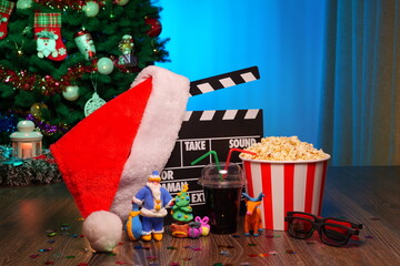 Merry Christmas and New Year Holidays Scene. Santa Claus Hat, Movie Clapperboard, Christmas Tree, Garland, Neon Lights, Cinema Popcorn, and 3D Glasses. Perfect Setting for Holiday Movie Nights at Home