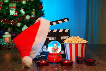 Merry Christmas and New Year Holidays Scene. Santa Claus Hat, Movie Clapperboard, Christmas Tree, Garland, Neon Lights, Cinema Popcorn, and 3D Glasses. Perfect Setting for Holiday Movie Nights at Home