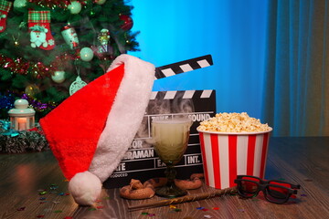 Merry Christmas and New Year Holidays Scene. Santa Claus Hat, Movie Clapperboard, Christmas Tree, Garland, Neon Lights, Cinema Popcorn, and 3D Glasses. Perfect Setting for Holiday Movie Nights at Home
