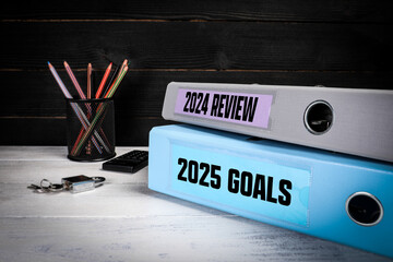 2024 Review and 2025 Goals. Two binders on desk in the office. Business background
