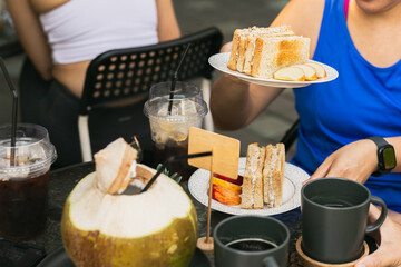 Woman hand holding tuna sandwich on a white plate in cafe.