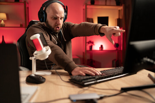 surfing the Internet with headphones. Millennial man plays computer games at home. Male player upset and angry about the defeat.