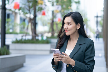 Fototapeta premium Asian businesswoman engaged on phone urban lifestyle professional context modern environment candid viewpoint business concept